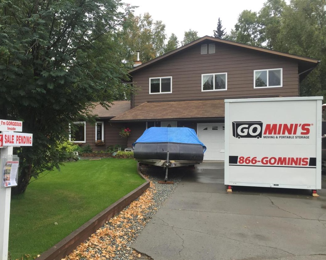 go minis storage container next to covered boat in front of house